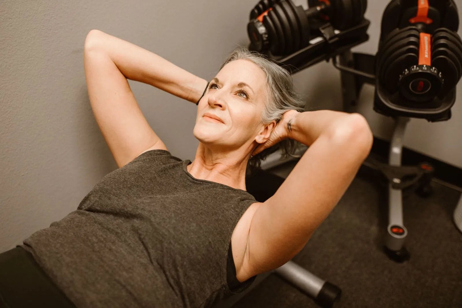 A strong woman over 50 training beside a rack of dumbbells