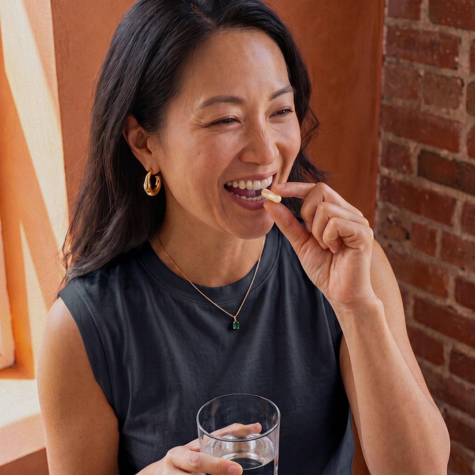 Woman taking a capsule while holding a glass of water