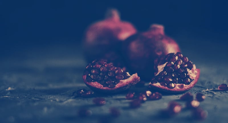 A halved pomegranate on a dark surface